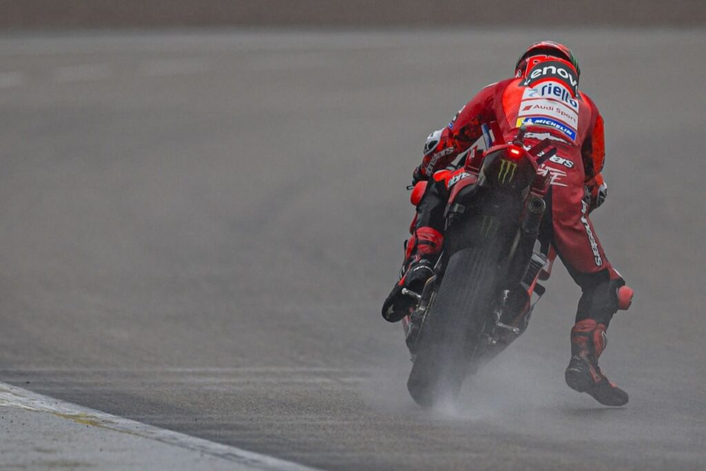 Francesco Bagnaia med sprint dirko na mokrem Sachsenringu 2025, medtem ko se bori z oprijemom zadnjega kolesa.